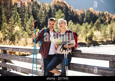 Austria, Alps, happy couple on a hiking trip with map on a bridge Stock Photo