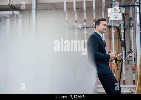 Thoughtful businessman with tablet PC in greenhouse Stock Photo