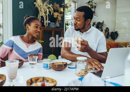 Father and daughter using a laptop at breakfast table Stock Photo