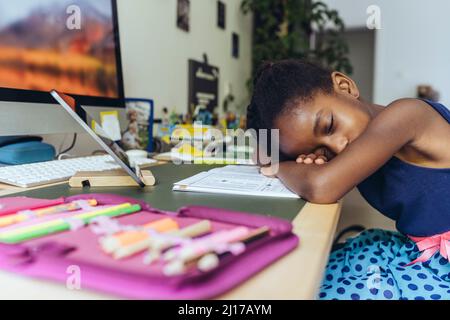 Tired girl resting head on desk at home Stock Photo