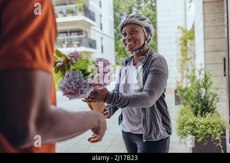 Smiling delivery woman giving flower bouquet to man at doorway Stock Photo