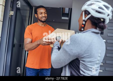 Customer receiving package box from delivery woman at doorway Stock Photo