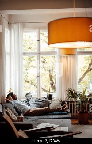 Man lying on sofa in living room at home Stock Photo