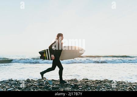 Man with surfboard running on beach Stock Photo