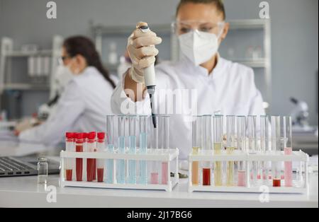 Female scientist working with pipette and glass tubes in pharma or biotech laboratory Stock Photo
