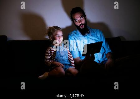 Father and son watching tablet PC together in living room Stock Photo