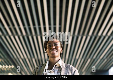 Smiling businesswoman standing under ceiling Stock Photo