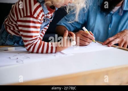 Father and son drawing on paper together at home Stock Photo