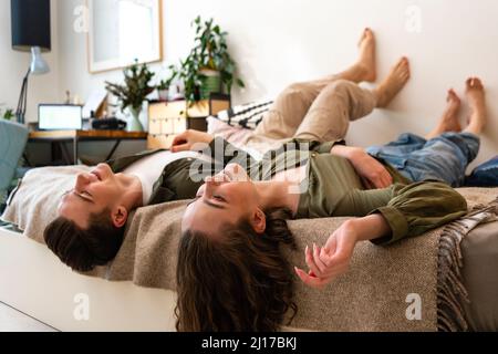 Smiling young couple lying on bed at home Stock Photo