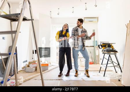 Cheerful couple renovating home and dancing in living room Stock Photo