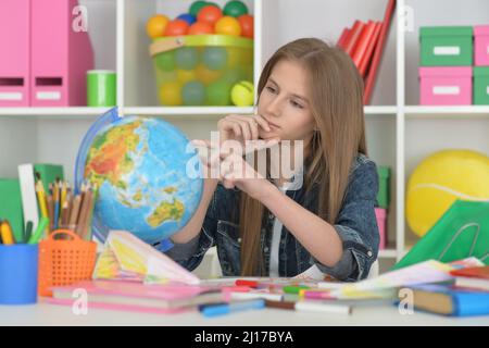 Girl siting at table with globe and studying Stock Photo