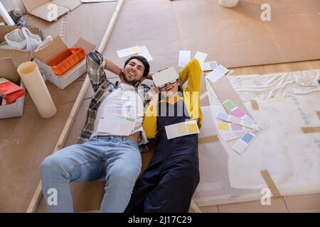 Young woman with VR glasses lying by boyfriend at new home Stock Photo