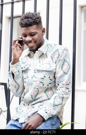 Smiling man talking on mobile phone by fence Stock Photo