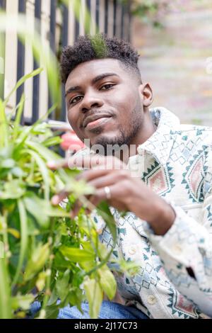 Young man with black hair touching plants Stock Photo