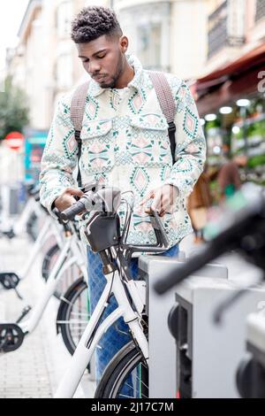 Man unlocking bicycle through smart phone at parking station Stock Photo