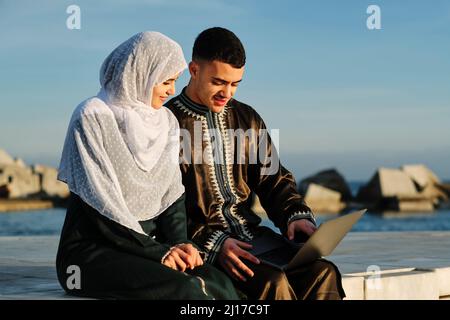 Young woman sitting by man using laptop Stock Photo