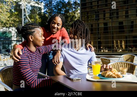 Smiling young woman talking with friends at sidewalk cafe Stock Photo