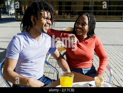 Smiling couple sitting at sidewalk cafe on sunny day Stock Photo