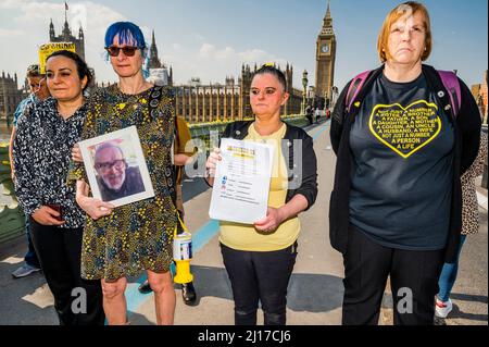 London, UK. 23rd Mar, 2022. Covid 19 Families UK (a support group for people who have lost people through Covid) mark the second anniversary of the first lockdown with a minutes silence on Westminster Bridge as part of a Marie Curie Day of Reflection. They also lay daffodils and tie a yellow ribbon. Credit: Guy Bell/Alamy Live News