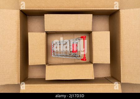 Shopping cart inside open rectangular cardboard box. Online internet shopping concept, e-commerce Stock Photo