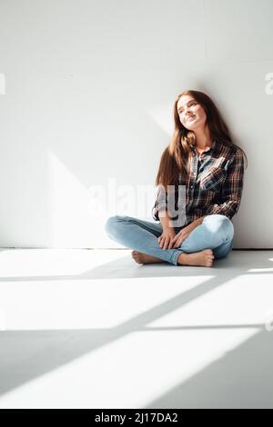 Contemplative woman sitting in front of wall Stock Photo - Alamy