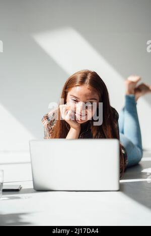Smiling woman using laptop at home Stock Photo