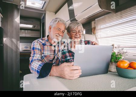 Smiling senior couple using laptop in camper van Stock Photo