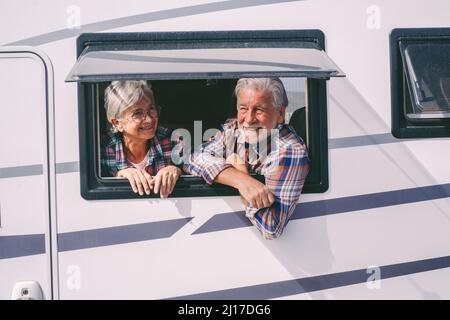 Happy senior couple looking through window of camper van Stock Photo