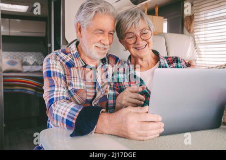 Happy senior couple using laptop in camper van Stock Photo