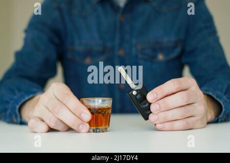 Drink no drive concept. Man holding car key and shot of whisky. Stock Photo