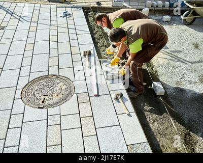 Pavers working on footpath installing paving stones Stock Photo