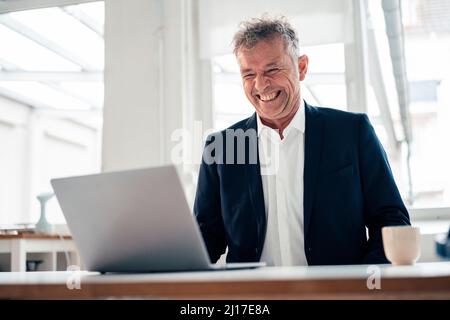Happy businessman using laptop in office Stock Photo