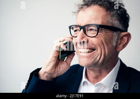 Cheerful businessman talking on smart phone at studio Stock Photo