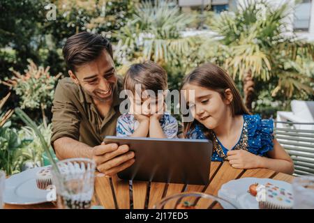 Father and children using tablet PC in back yard Stock Photo