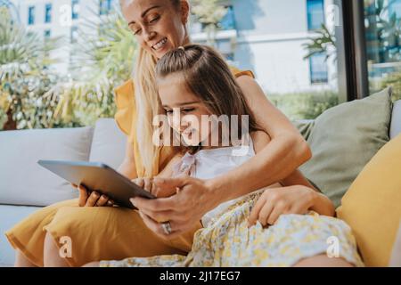 Happy mother and daughter using tablet computer in patio Stock Photo