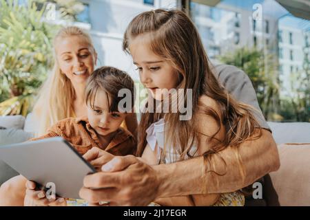 Father and children using tablet computer in patio Stock Photo