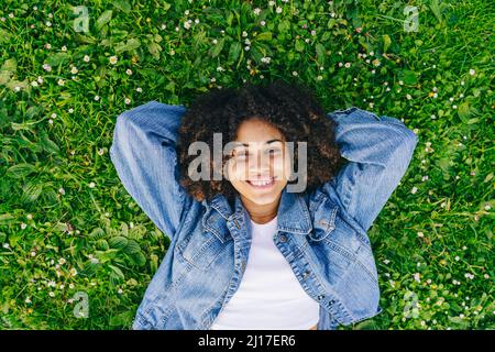 Young woman lying down with hands behind head on meadow Stock Photo