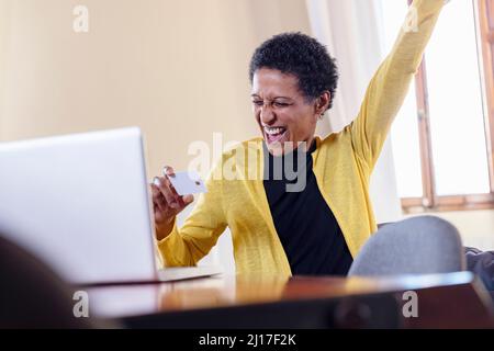 Cheerful freelancer with credit card and laptop at home Stock Photo