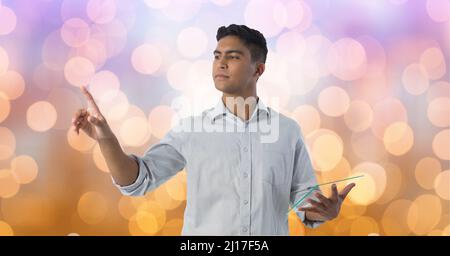 Man holding a futuristic digital tablet touching invisible screen against spots of light Stock Photo