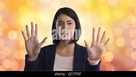 Portrait of asian businesswoman touching invisible screen against spots of light in background Stock Photo