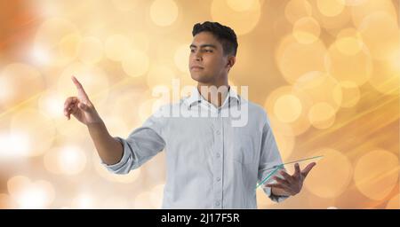 Man holding a futuristic digital tablet touching invisible screen against spots of light Stock Photo