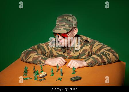 Military soldier with army figurines against green background Stock Photo