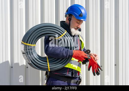 Engineer with cables wearing protective glove on sunny day Stock Photo