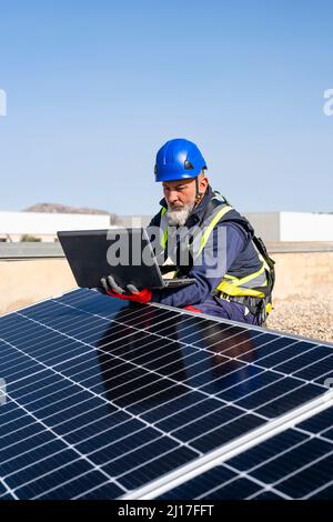 Engineer working on laptop by solar panels Stock Photo