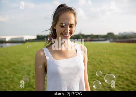 Happy young woman with soap bubbles on meadow Stock Photo