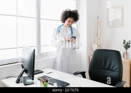 Doctor using mobile phone standing in medical office Stock Photo