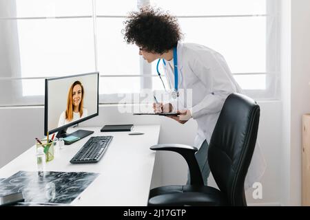 Doctor discussing with patient through video call at medical clinic Stock Photo