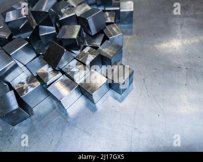 pile of small machined shiny steel cubes on metal surface Stock Photo