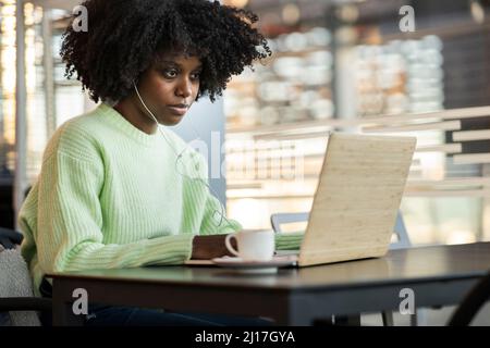 Woman using laptop sitting in cafe Stock Photo