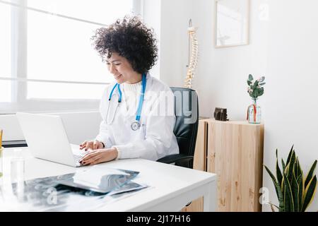 Smiling doctor using laptop at medical clinic Stock Photo